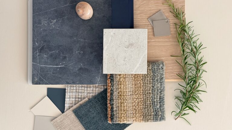 Interior design material palette with blue stone, creamy quartz, navy cabinetry, warm oak, layered textured fabrics, brushed nickel hardware, rosemary, and a shell.