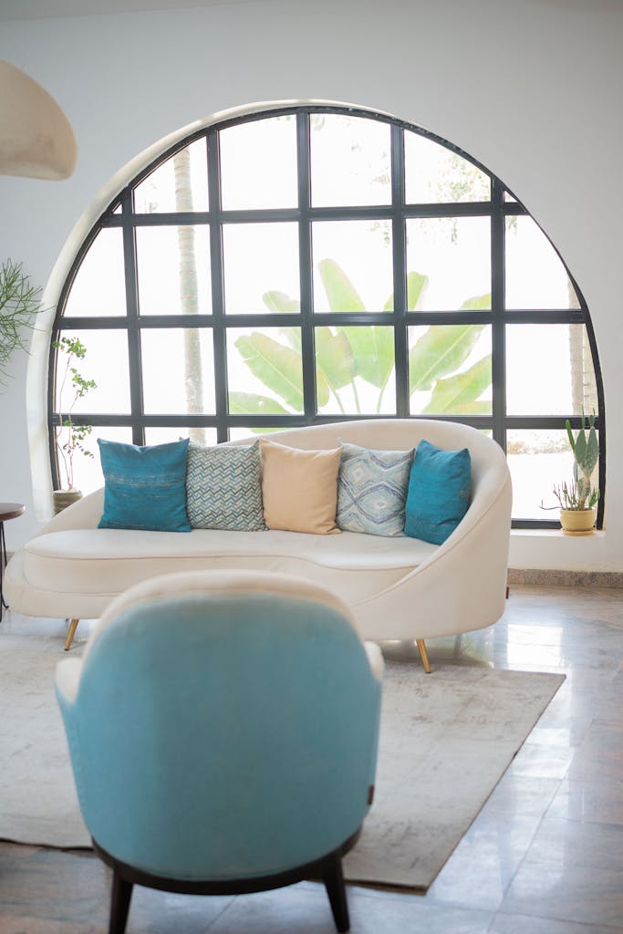 Elegant living room featuring a stylish sofa and a large circular window with lush greenery outside.