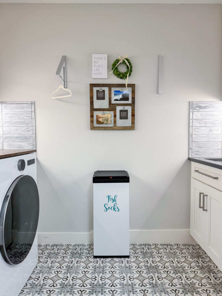 Laundry room after a renovation with washer and dryer, custom white cabinets, and utility sink with patterned tile floor, subway tile backsplash, and quartz countertops.
