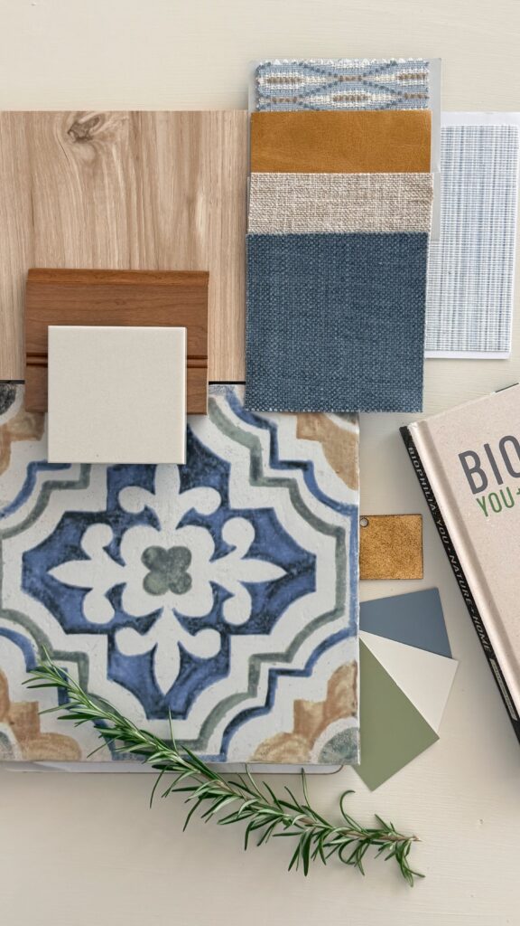 Interior design material palette featuring blue and white patterned tile, white quartz, textured blue and neutral fabrics, warm wood tones, and a design book inspired by nature.